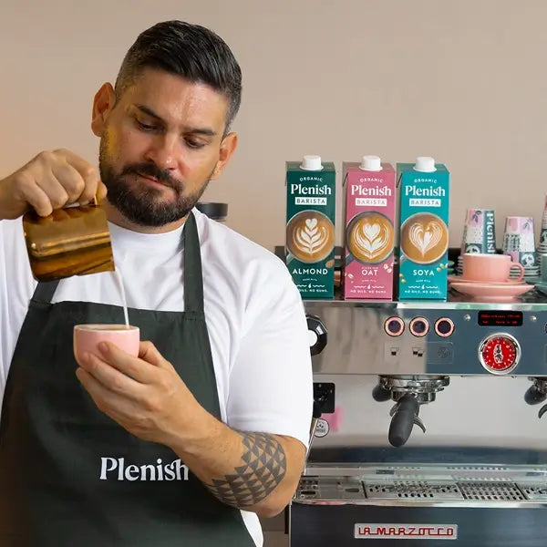 Plenish Barista making coffee in front of coffee machine and Plenish plant milks